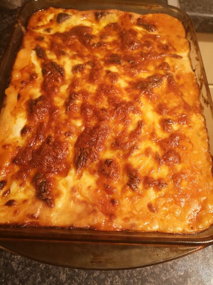 Baked cheesy casserole dish with a golden brown crust, shared in a Facebook group where people rate others' dishes.