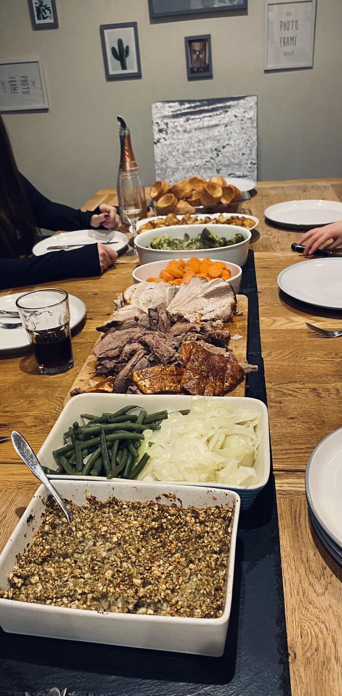Dinner spread featuring roasted meat, vegetables, and side dishes on a wooden table for Facebook group dish ratings.