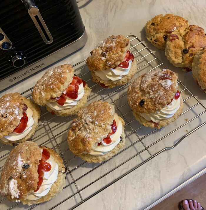 Homemade cream and jam scones cooling on a rack, featured in a Facebook group where people rate others' dishes.