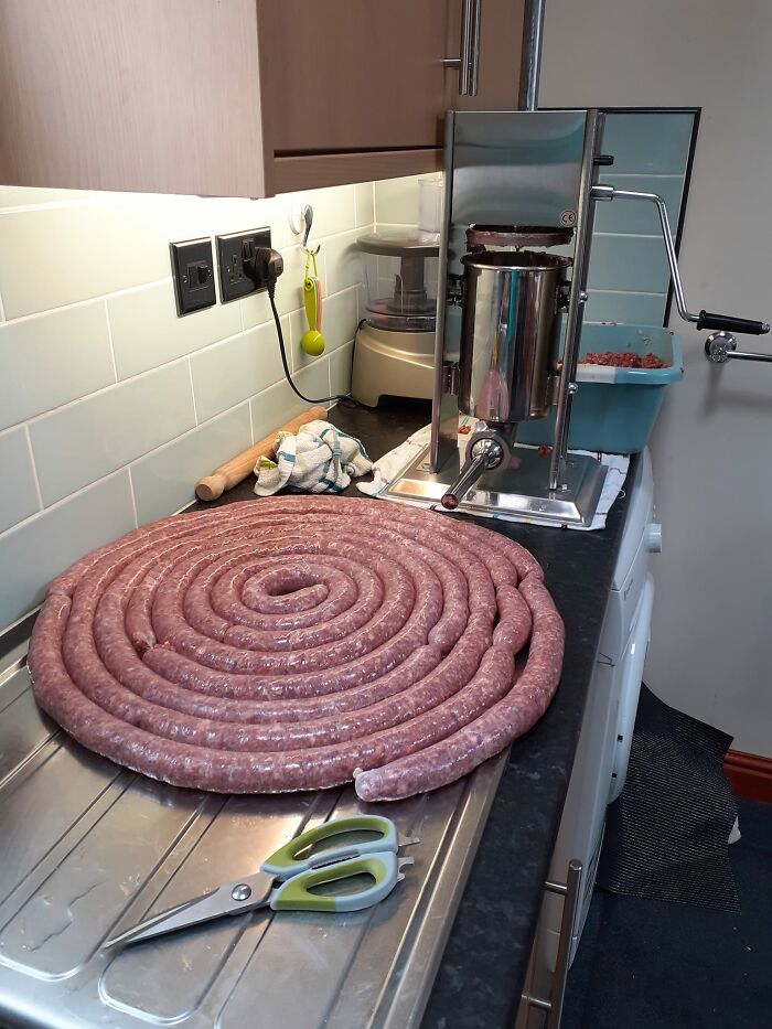 Large coiled sausage being made in a kitchen, showcasing a dish rated by people in a Facebook group for dishes.