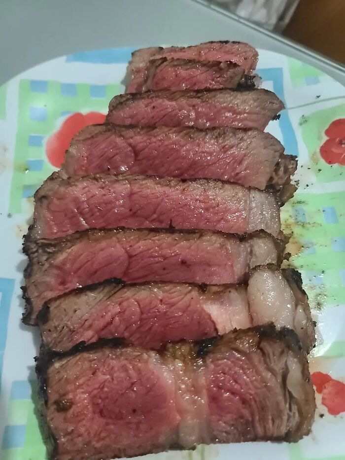 Sliced rare cooked steak arranged on a colorful plate, featured in a Facebook group where people rate others' dishes.