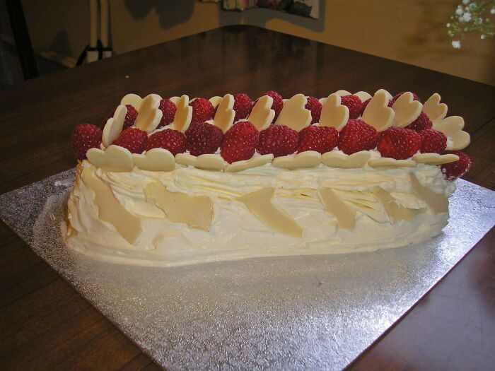 Creamy dessert dish decorated with raspberries and white chocolate hearts on a silver board in a food rating Facebook group.