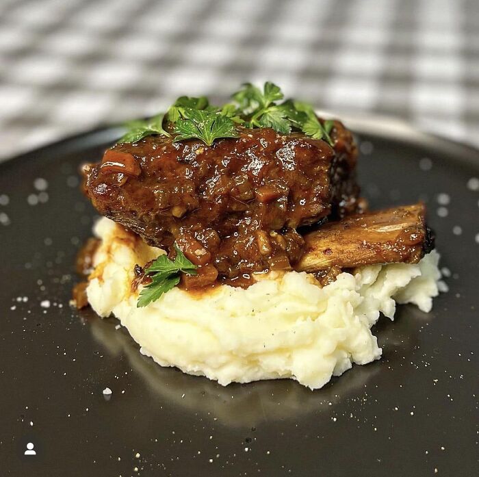 Braised meat dish with rich gravy served on creamy mashed potatoes, featured in a popular group rating others' dishes.