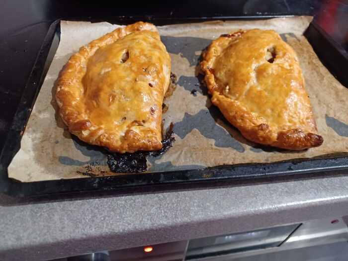 Two golden-brown baked dishes on parchment paper in an oven, featured in a Facebook group rating others' dishes.