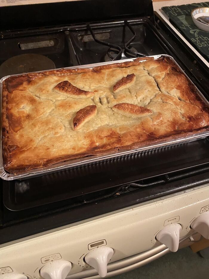 Baked homemade dish with golden crust and decorative leaf-shaped pastry on top, from a Facebook group rating others' dishes.