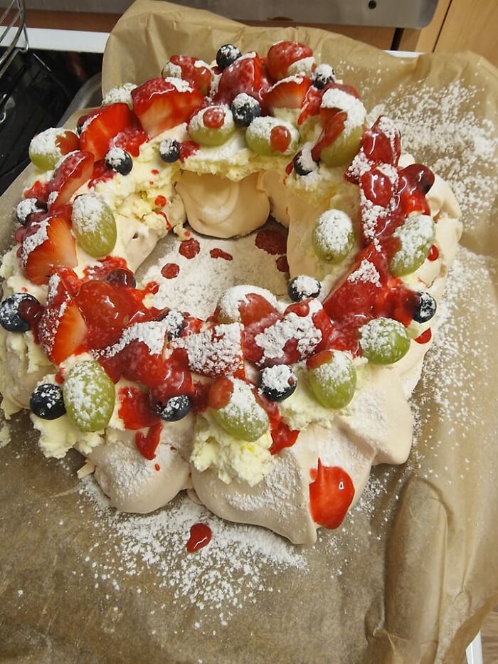 Decorated dessert with whipped cream, fresh berries, and powdered sugar, featured in a Facebook group rating dishes.