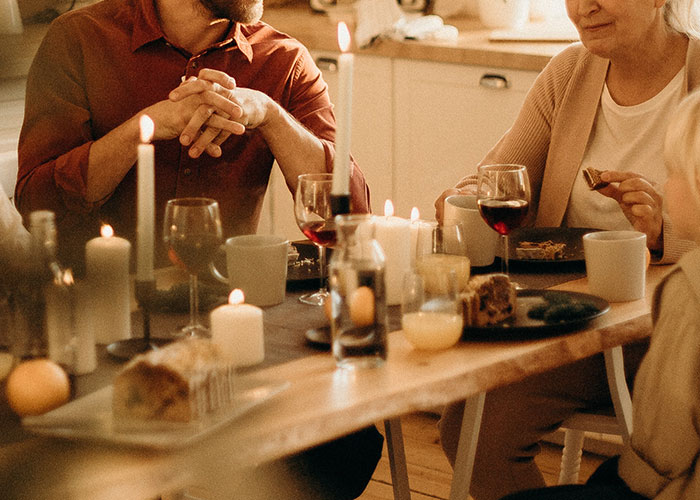 Group of men and women sitting at a candlelit dinner table, discussing common annoying experiences related to their gender.