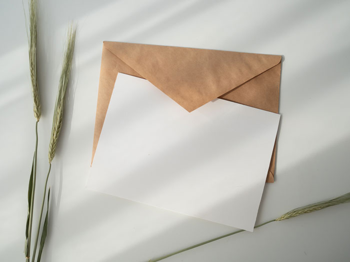 Envelope with blank card, a cool New Year's Eve item, on a white surface with decorative grass.
