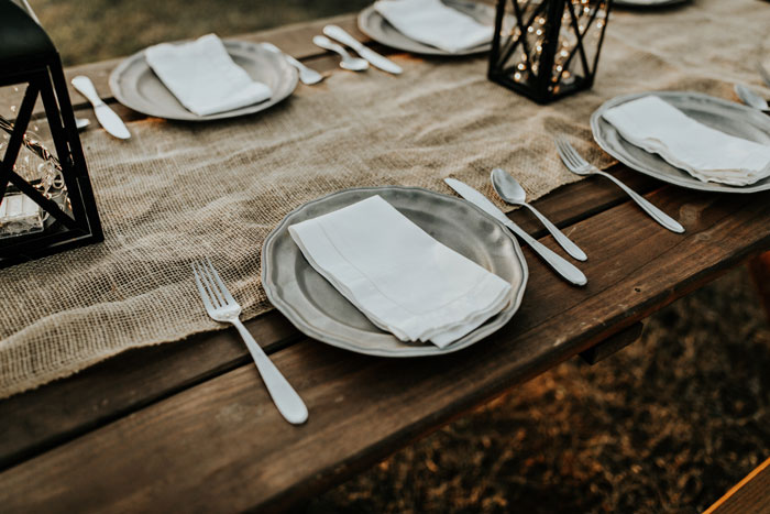 Festive New Year's Eve table setting with plates, cutlery, and lanterns on a rustic wooden table.