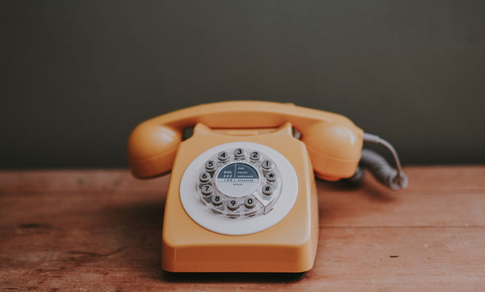 Yellow vintage rotary phone on a wooden table, evoking nostalgia on New Year's Eve.