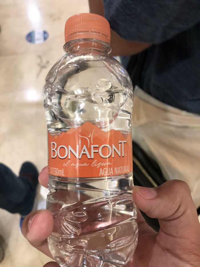 Hand holding a small Bonafont natural water bottle in a casual indoor setting, illustrating a never again brand example.