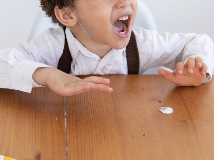 Young boy angrily gesturing on wooden table, illustrating how good intentions can sometimes lead to bad outcomes.