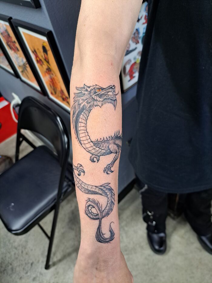 A detailed dragon tattoo on a person's forearm, showcasing the intricate design and shading.