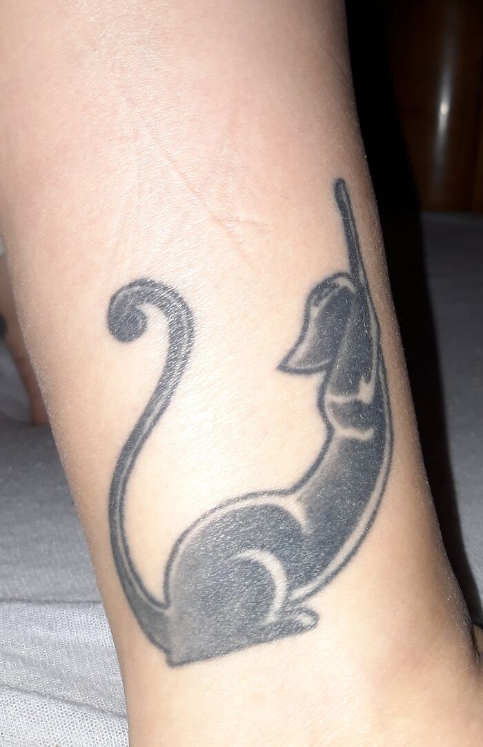 Stylized black cat tattoo on forearm.