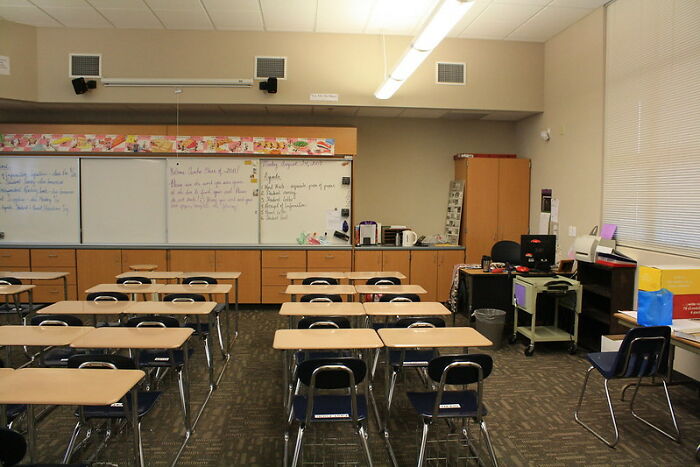 Empty classroom with rows of desks and chairs, whiteboards filled with notes, illustrating good intentions gone wrong.