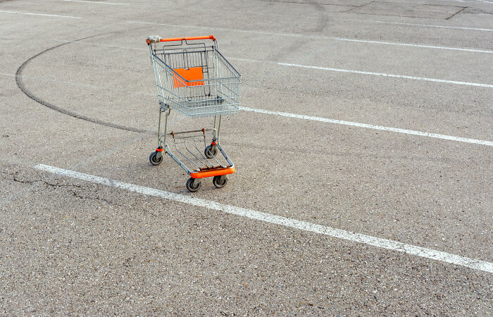 Empty shopping cart with orange accents in an almost empty parking lot illustrating basic facts about common observations.