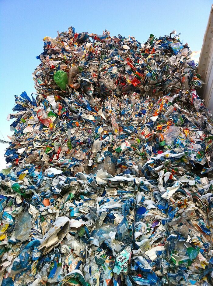 Large pile of mixed plastic waste against a clear blue sky illustrating consequences of good intentions ending badly.
