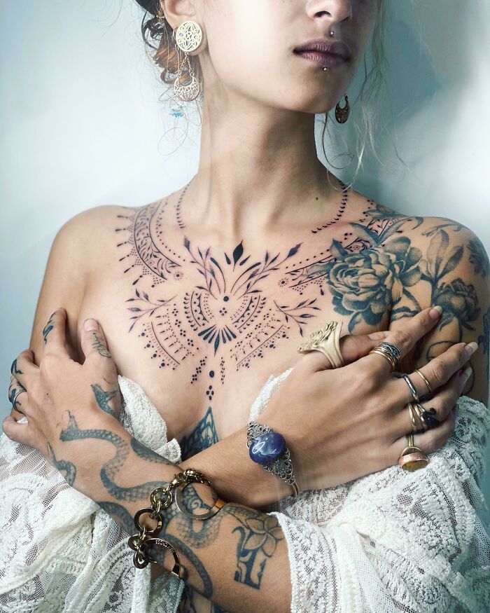 Intricate and beautifully executed tattoo design on a woman's chest and arms, showcasing artistic creativity.