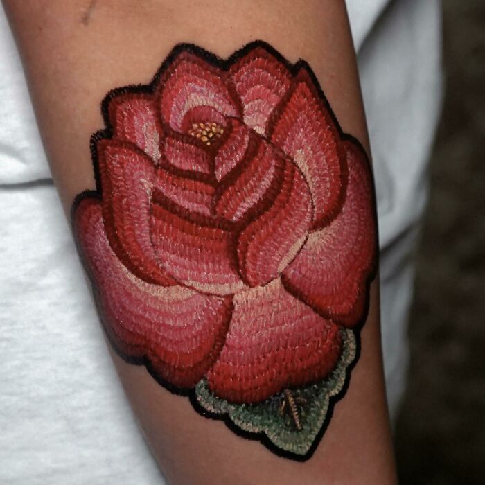 Beautifully executed rose tattoo on forearm, showcasing intricate design and rich colors.