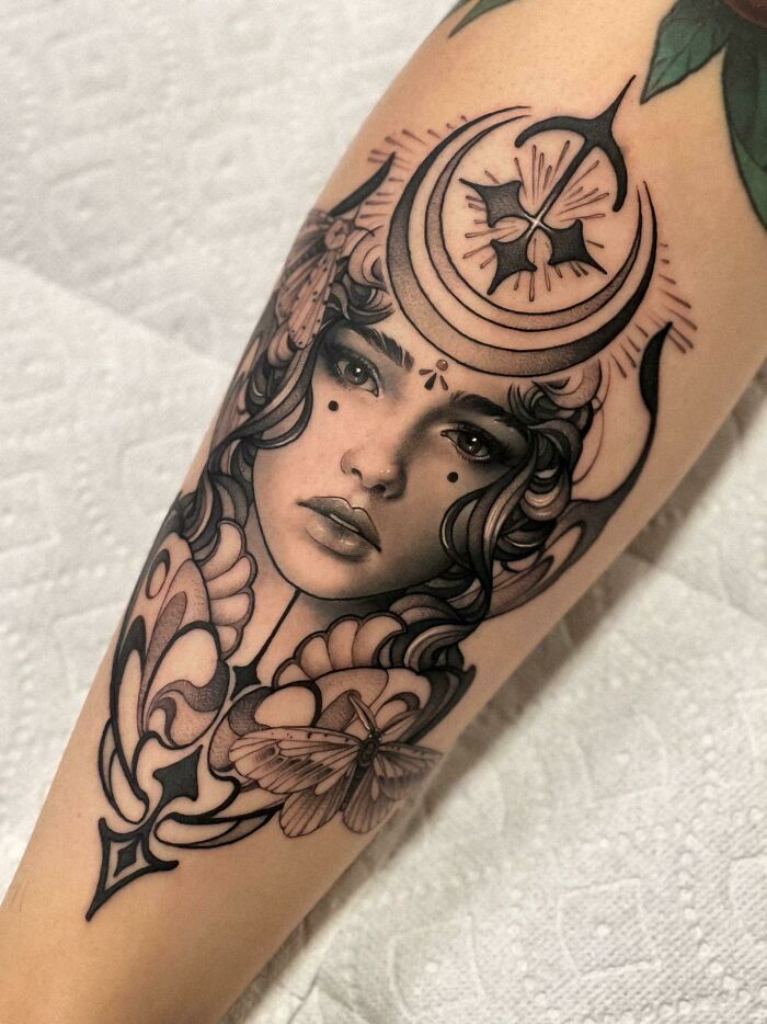 Beautiful tattoo idea of a woman's face with crescent moon and moth, perfectly executed on forearm.