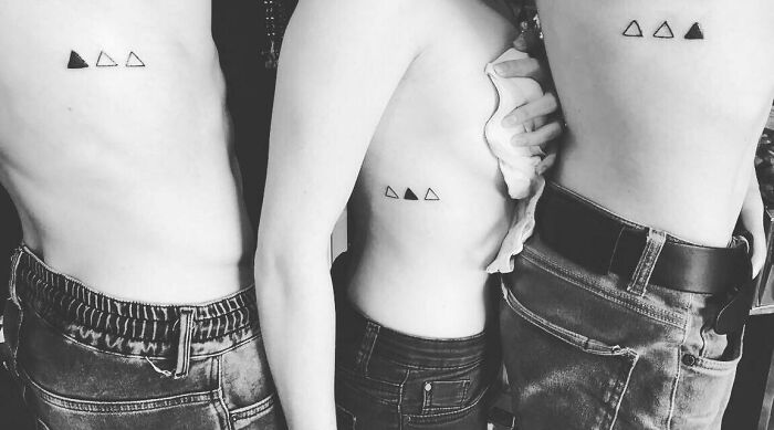 Three people with matching triangle tattoos on their ribs, showcasing a beautifully executed tattoo idea.