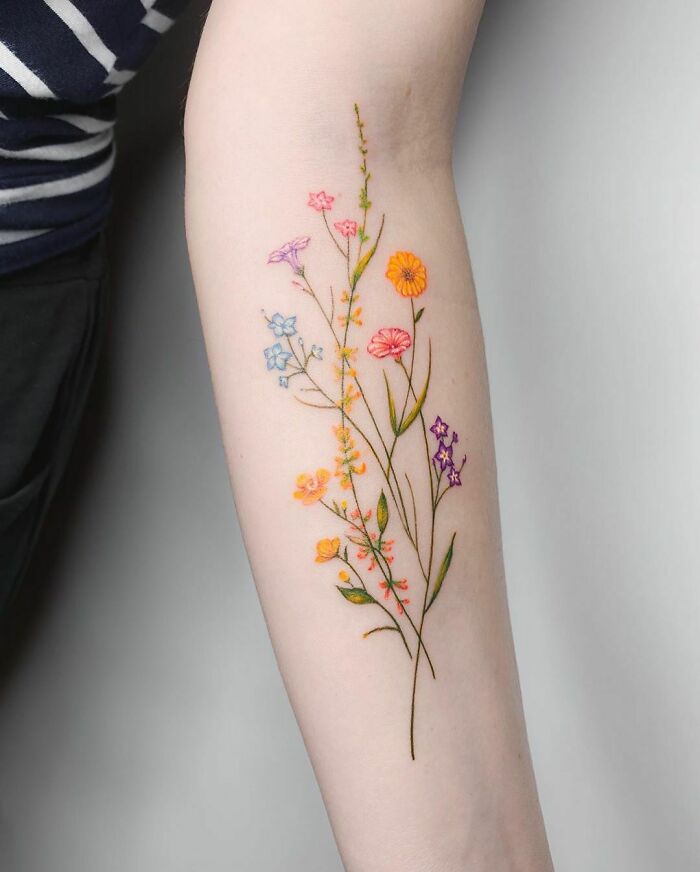 Colorful floral tattoo perfectly executed on forearm, showcasing a beautiful tattoo idea with delicate flower details.