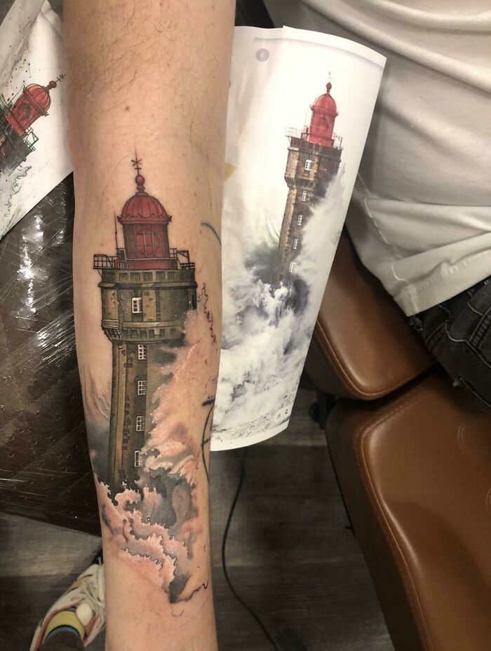 Beautiful lighthouse tattoo flawlessly executed on a person's forearm, showcasing vibrant details and artistry.
