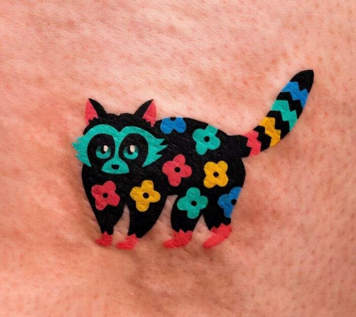 Colorful raccoon tattoo with floral patterns, executed perfectly on skin.