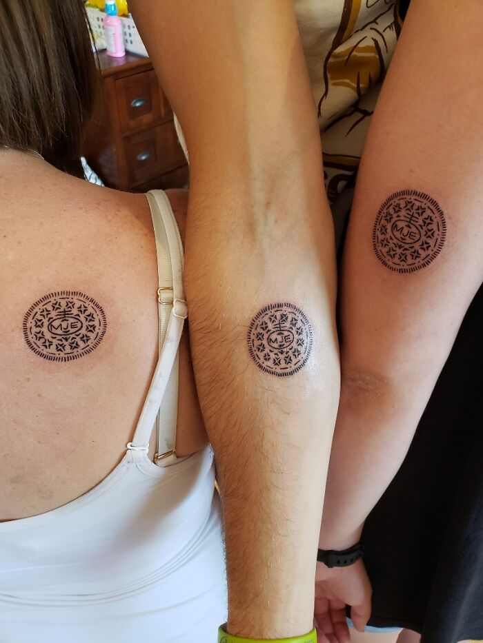 Matching sibling tattoos with intricate circular designs on shoulder and forearms.