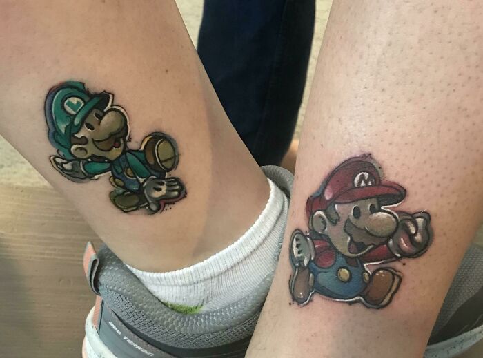 Brother and sister tattoos of Mario and Luigi characters on legs.