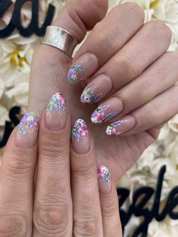 Nails with delicate floral nail art designs in pastel colors on a n**e base, showcasing creative nail art ideas.