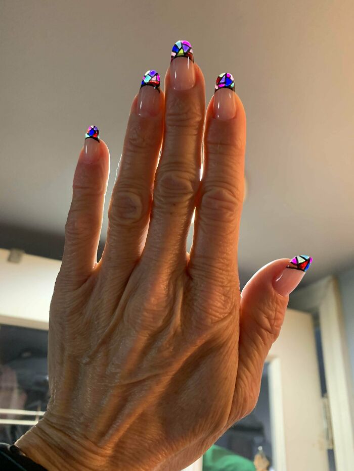 Hand with colorful stained glass inspired nail art tips showcasing creative nail art ideas for unique small artworks.
