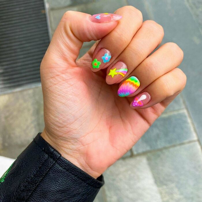 Colorful nail art with floral and star designs on a hand, great idea for your next nail appointment.