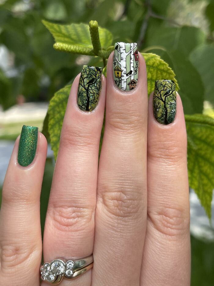 Green forest-themed nail art featuring trees and birdhouses.