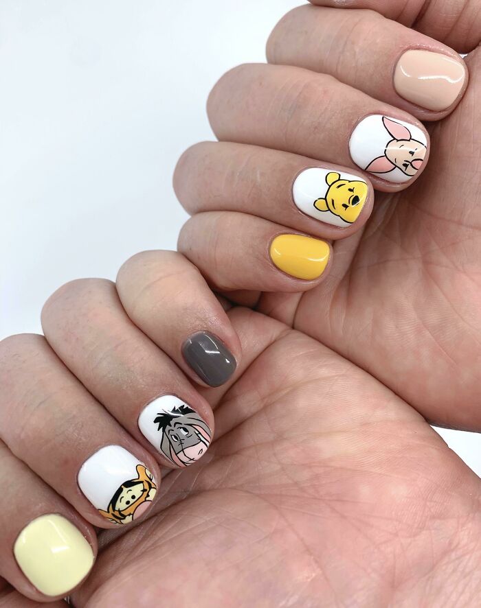 Playful nail art featuring cartoon characters with yellow, white, and gray accents. Perfect for your next nail appointment.
