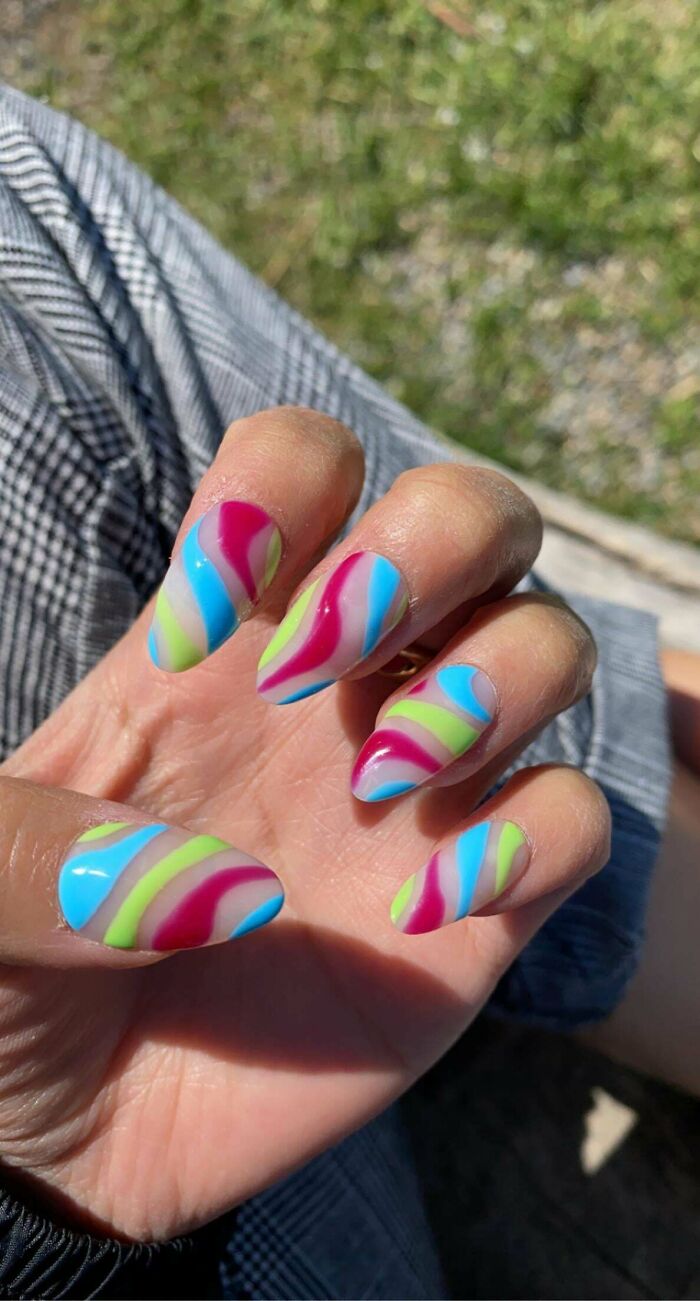 Colorful wavy nail art design on fingers, featuring shades of blue, pink, and green, perfect for your next appointment.