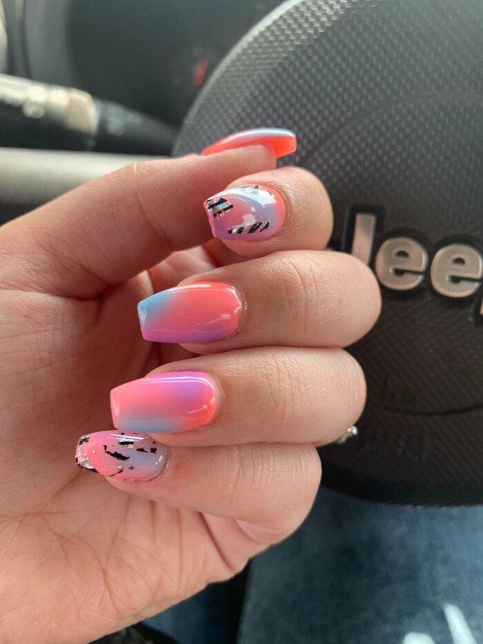 Vibrant nail art featuring pink and blue ombre with abstract black accents, ideal for your next appointment.