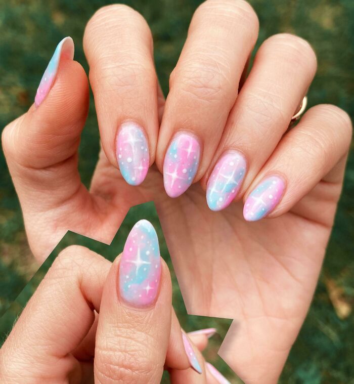 Pastel pink and blue nail art ideas featuring sparkles and small white dots on almond-shaped nails outdoors.