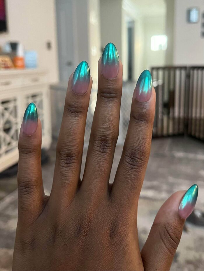 Metallic teal ombre nail art on a hand, showcasing a stylish nail design idea for your next appointment.