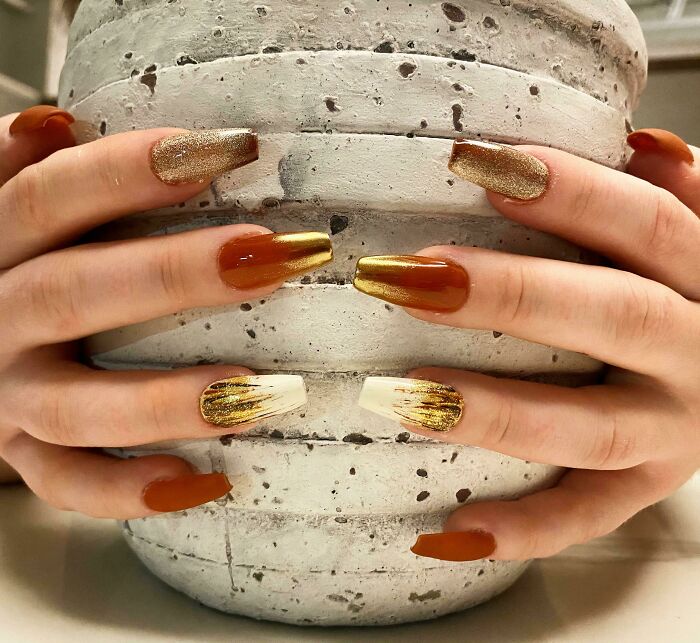 Creative nail art with gold and brown tones, wrapped around a textured gray pot. Perfect for your next appointment.