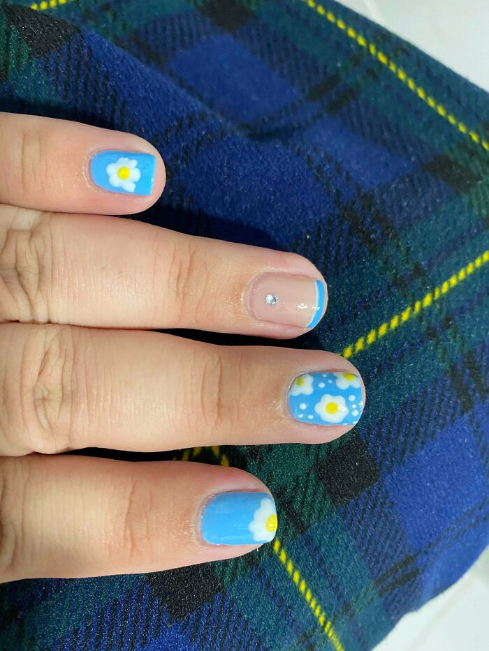 Blue and daisy nail art design on fingers, showcasing creative nail art ideas.