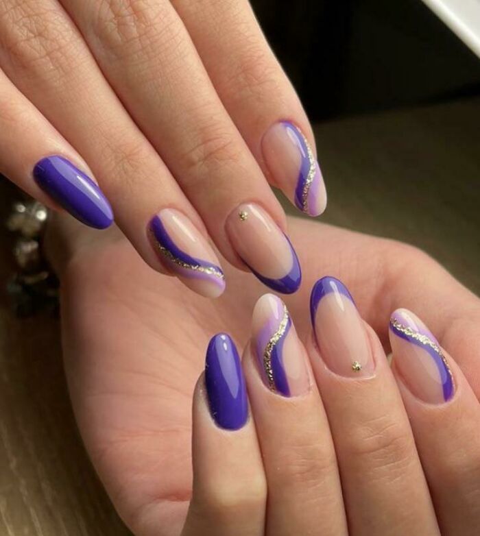 Elegant nail art with purple and gold accents on almond-shaped nails.