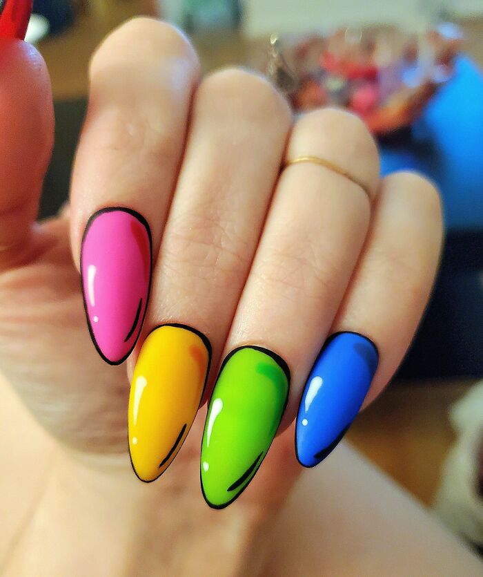Colorful nail art with bold shades of pink, yellow, green, and blue on a hand.