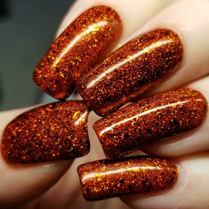 Glossy copper glitter nail art design on long nails showcasing creative nail art ideas for stylish manicures.