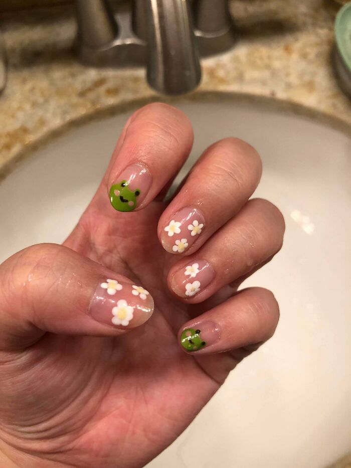 Cute floral and frog nail art design on hand, showcasing creative nail art ideas.