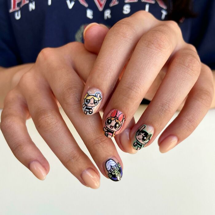 Nail art featuring detailed cartoon characters on natural nails, showcasing creative and colorful nail art designs.