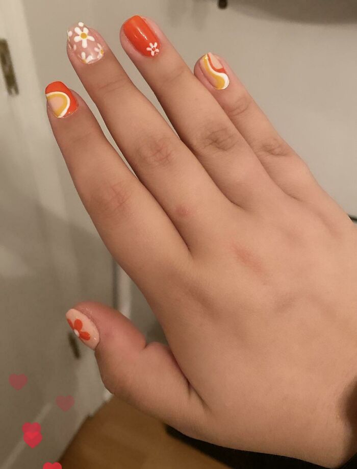 Vibrant nail art featuring orange and pink hues with floral and wave designs, perfect for your next nail appointment.