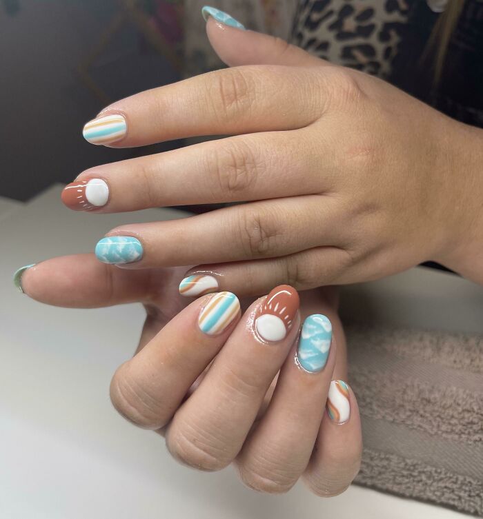 Colorful nail art ideas showcasing abstract patterns with blue, white, and orange designs for your next appointment.