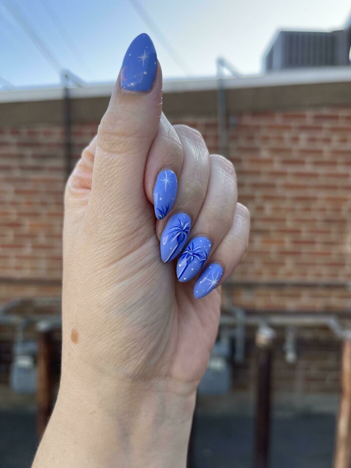 Blue nail art with white star designs, perfect for your next nail appointment.