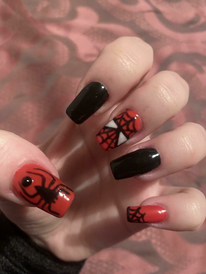 Spider-themed nail art with black and red designs featuring webs and spiders, ideal for your next nail appointment.